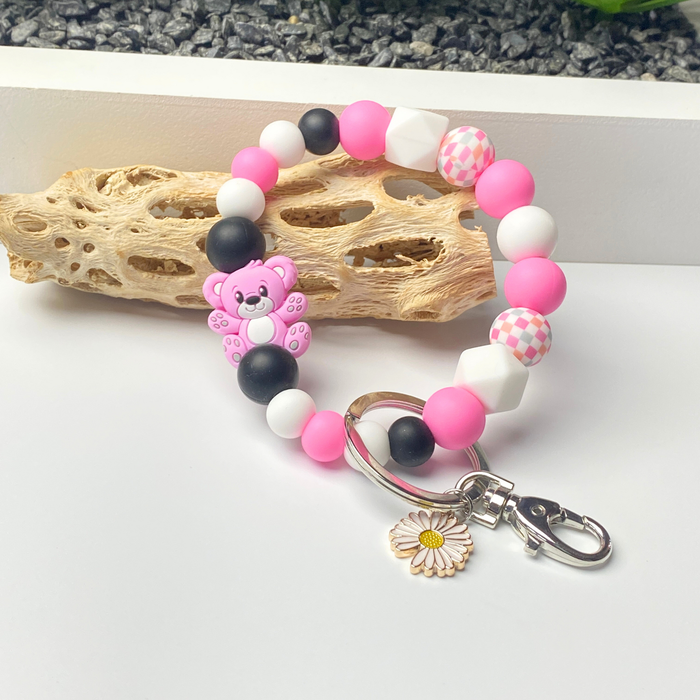 Beaded keychain with teddy bear charm and heart-shaped clasp on a white surface.
