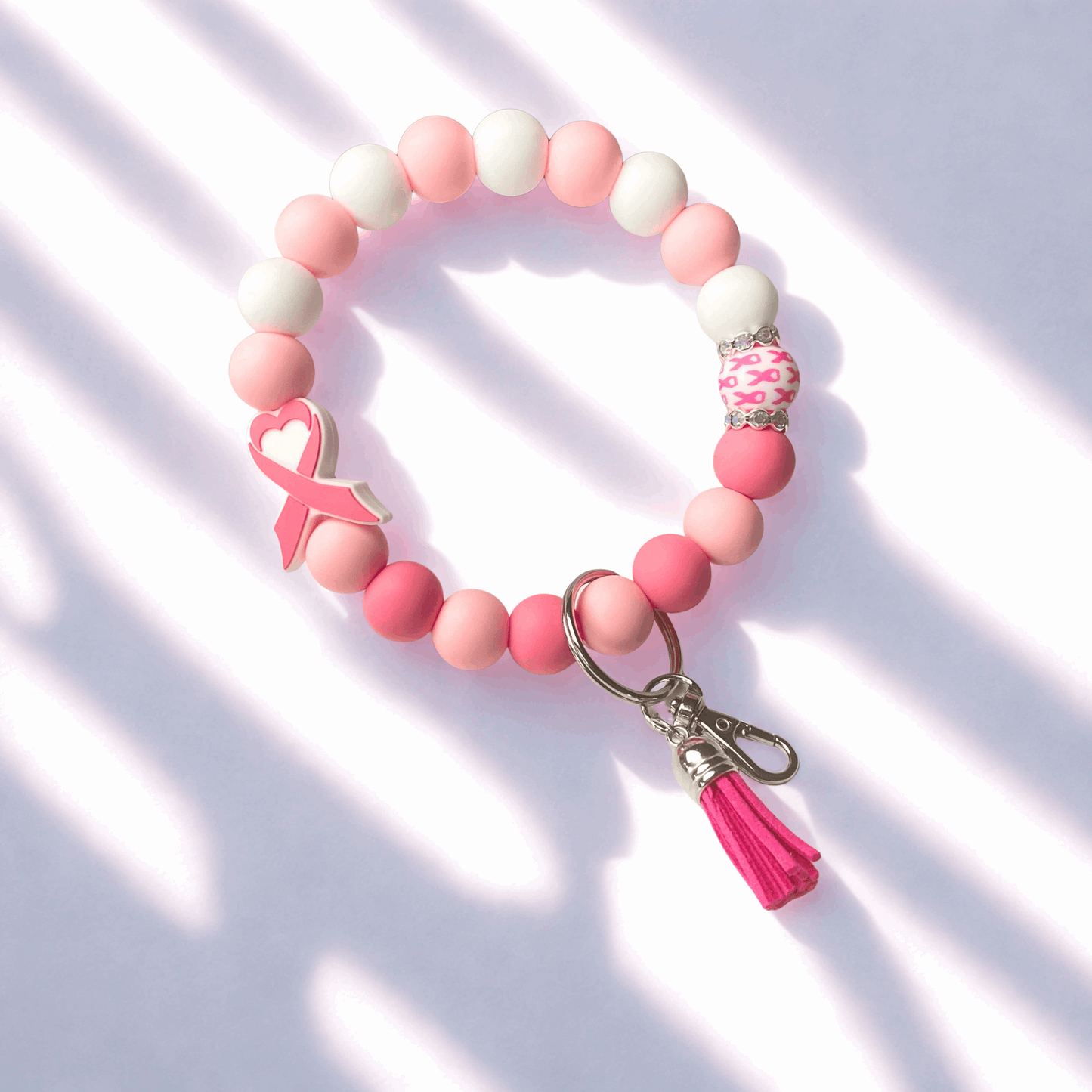 Pink and white beaded bracelet with a breast cancer awareness ribbon charm on a light background