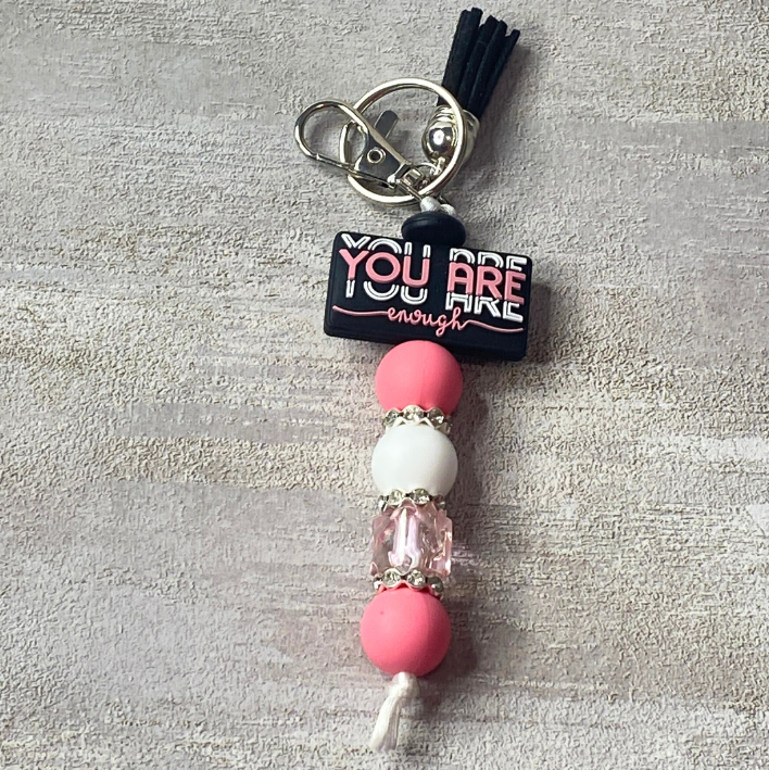 Keychain with beads and motivational quote on a textured surface