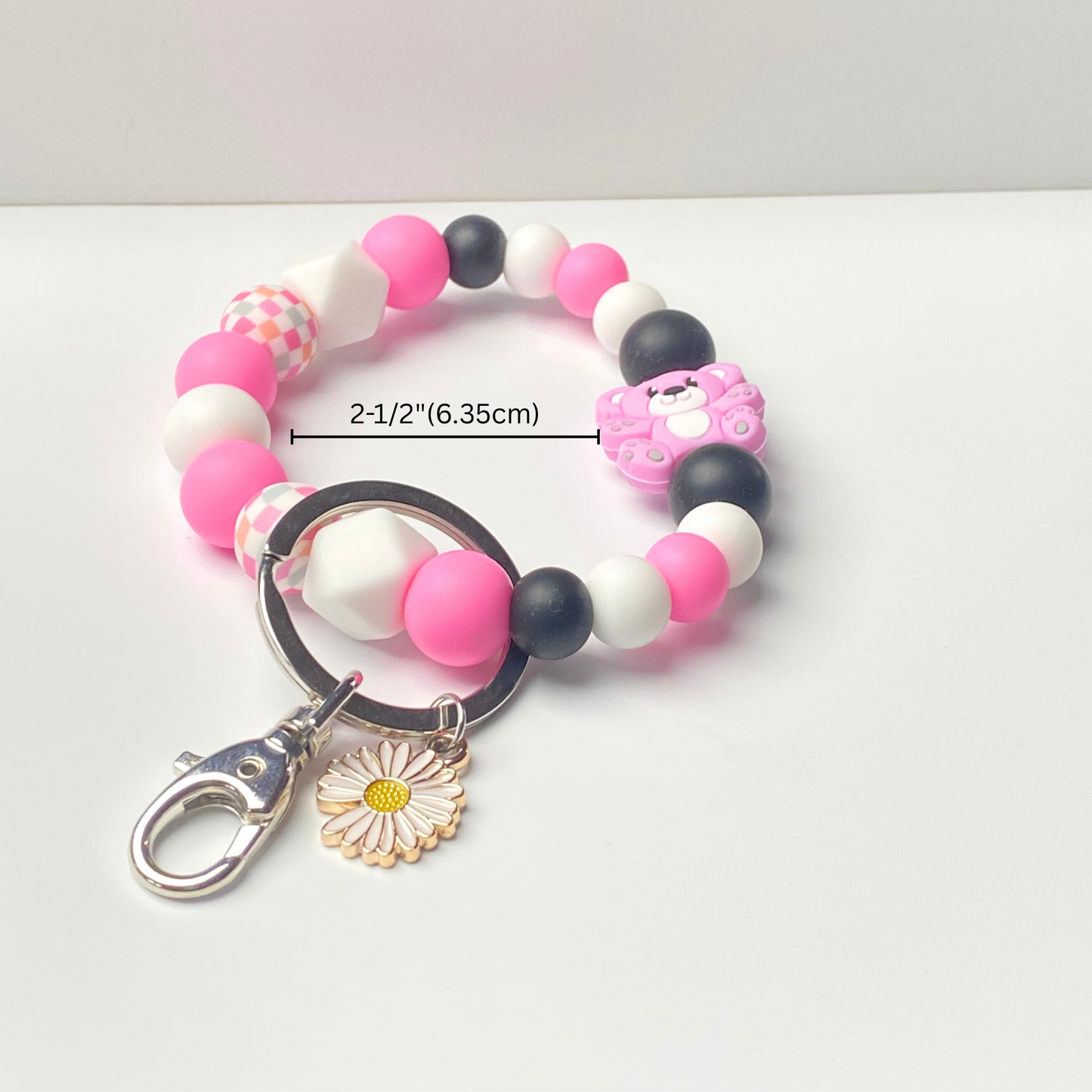 Beaded keychain with pink, black, and white beads on a white background