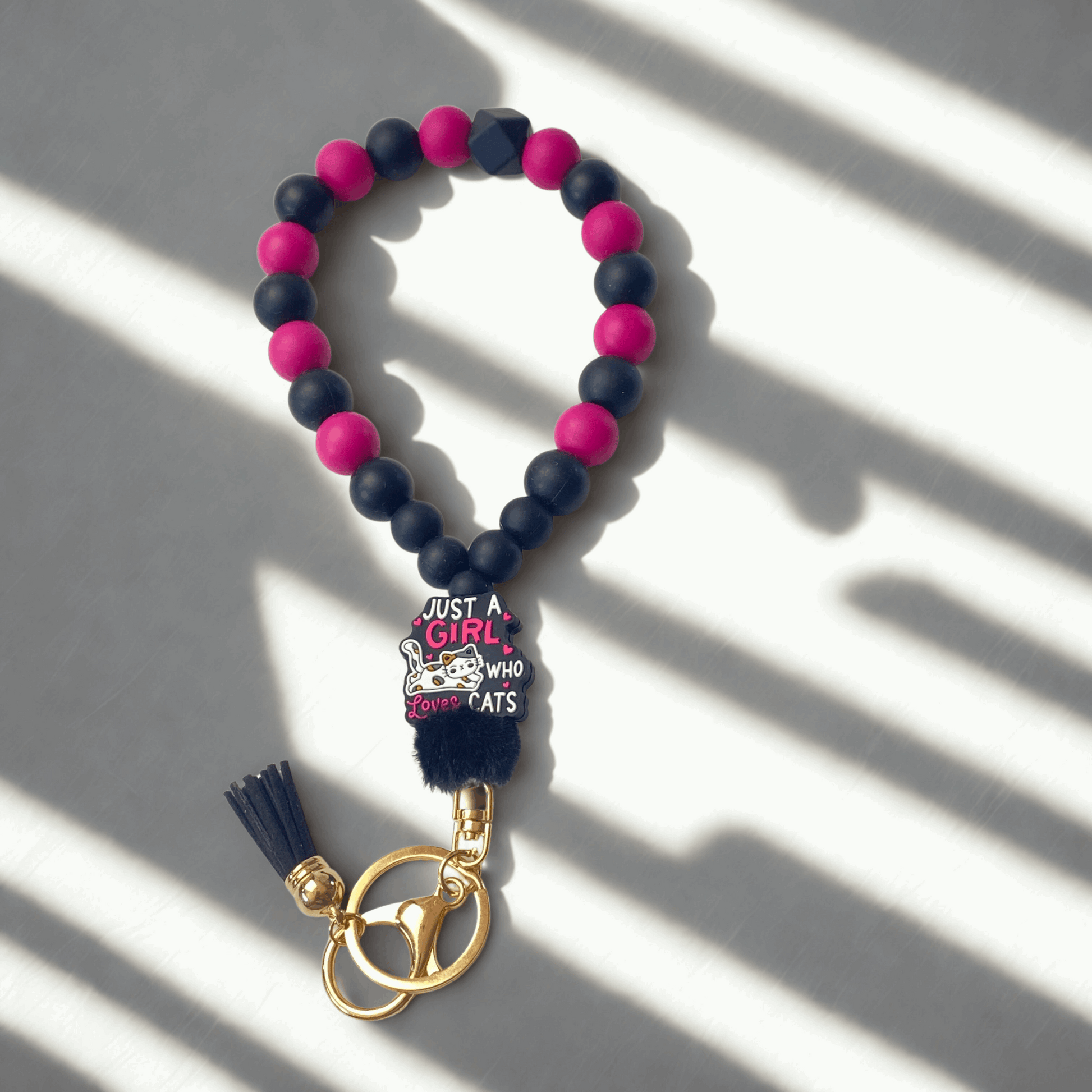 Beaded keychain with pink and navy blue beads and a gold clasp on a light background