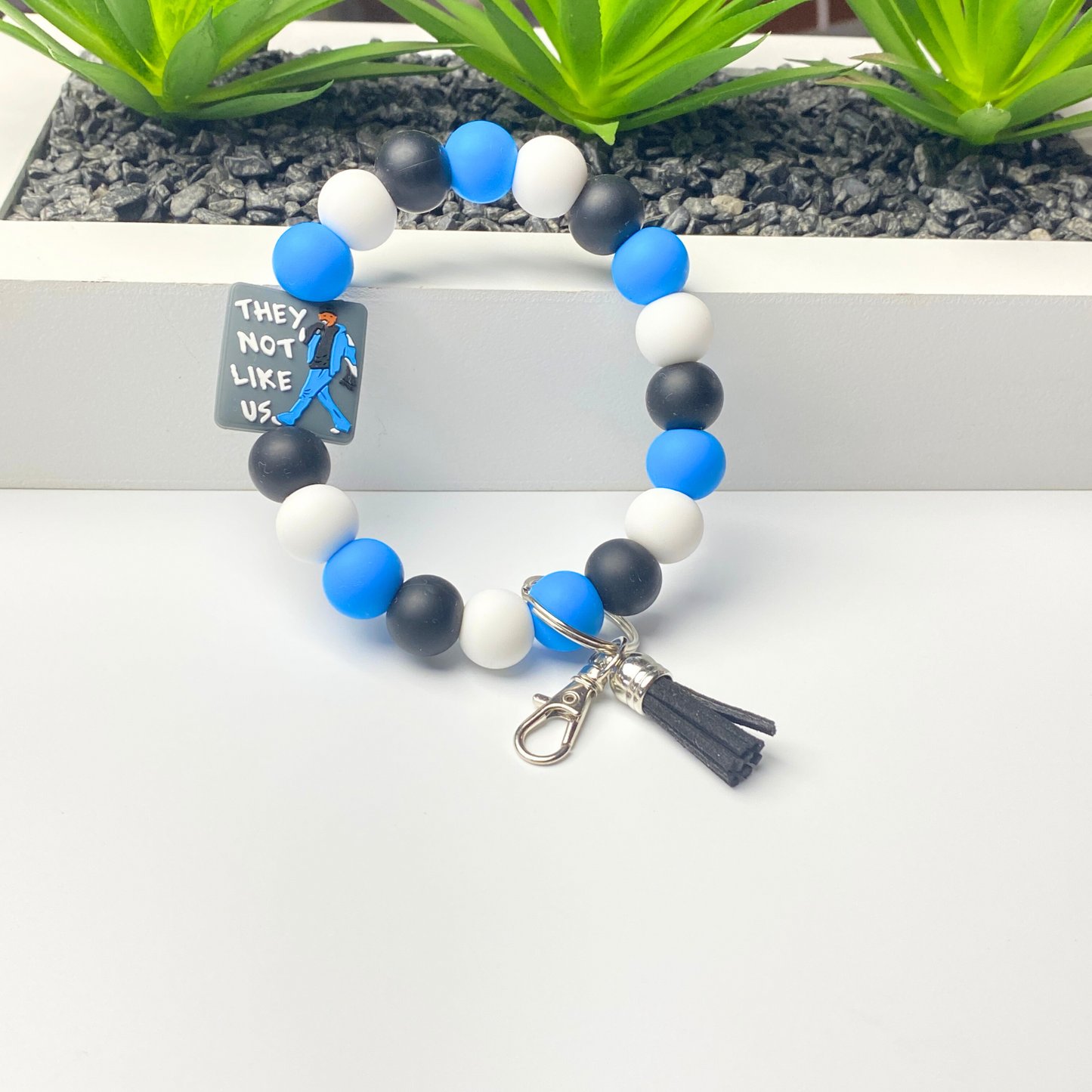 Beaded keychain with blue, black, and white beads on a white background