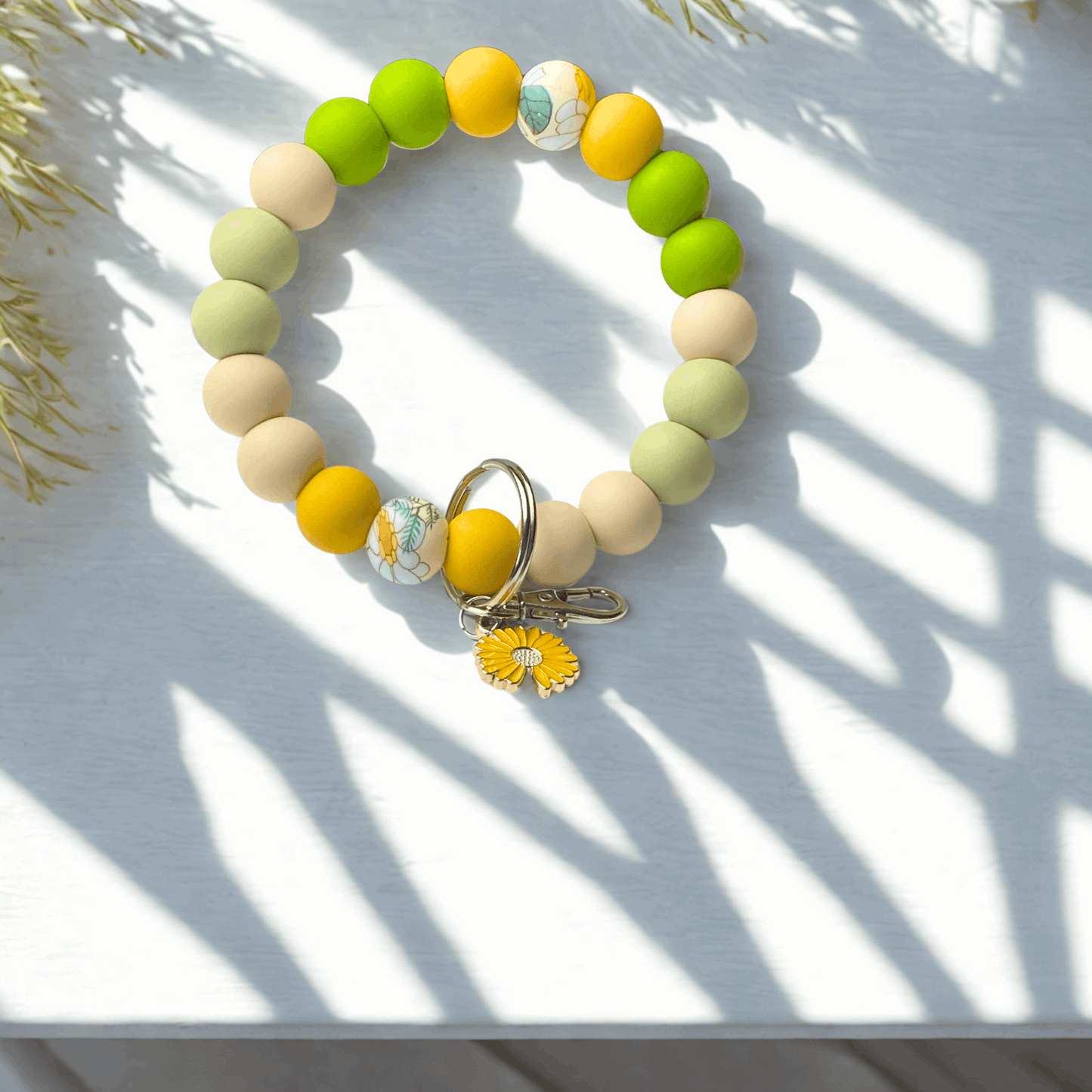 Colorful beaded bracelet with a keychain on a white surface with shadows
