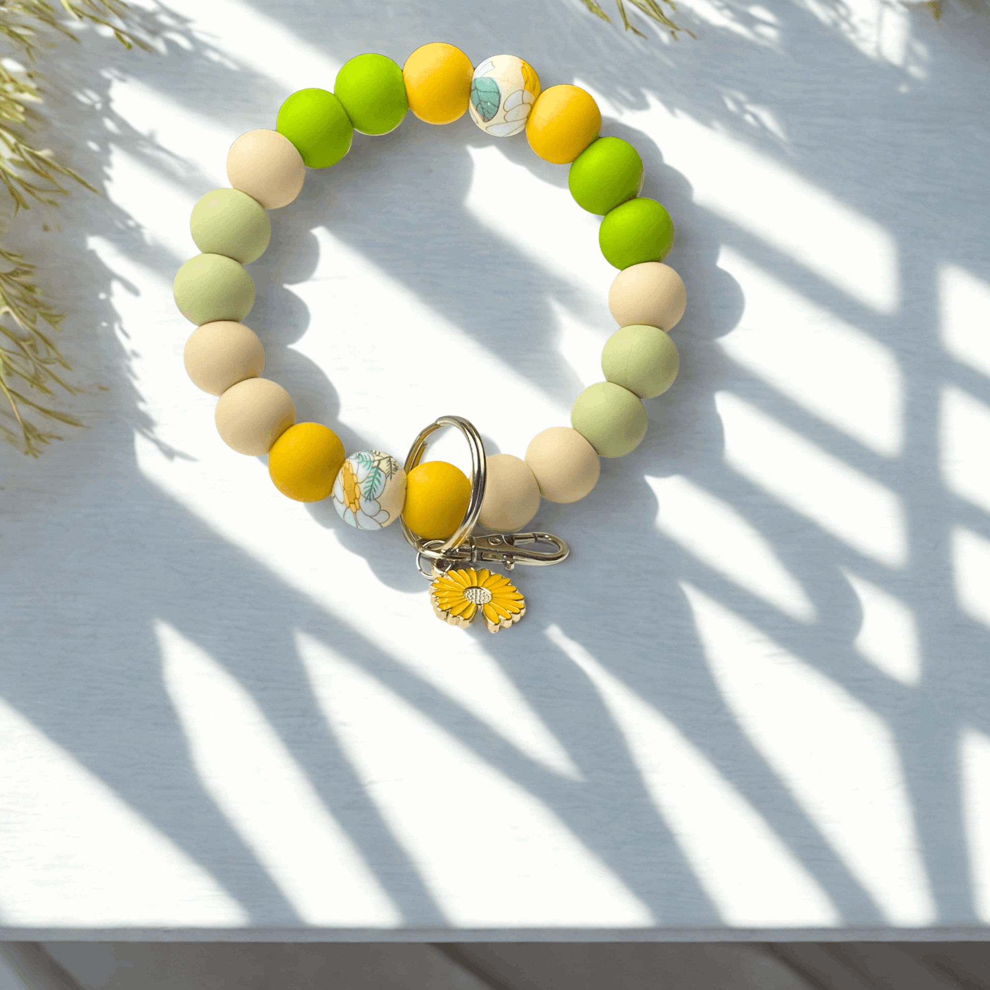 Colorful beaded bracelet with a keychain on a white surface with shadows