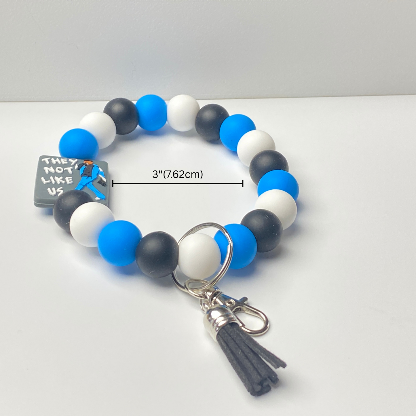 Beaded bracelet with blue, black, and white beads and a keychain on a white background