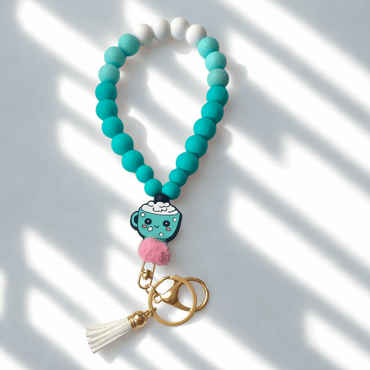 Turquoise beaded keychain with a cartoon character charm on a white background