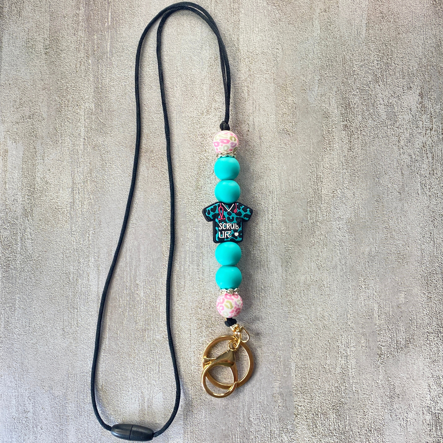 Lanyard with colorful beads and a keychain on a textured gray background