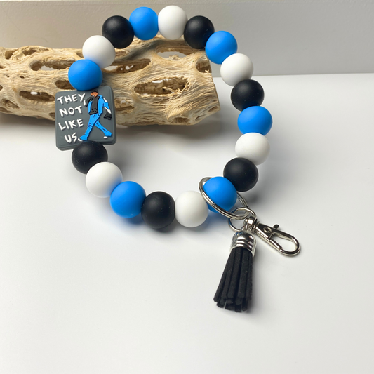 Bracelet with blue, black, and white beads and a tassel charm on a light background.