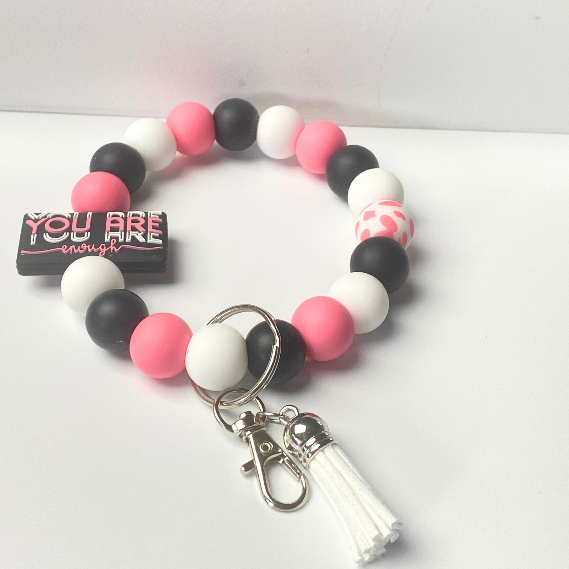 Beaded bracelet with pink, black, and white beads and a keychain on a white background.