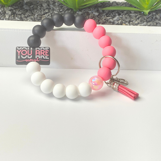 Bracelet with pink and white beads and a tassel on a white background