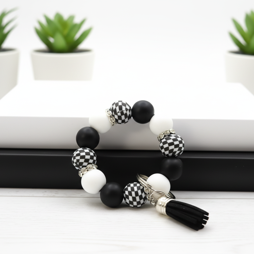 Black and white beaded bracelet on a white surface with green plants in the background