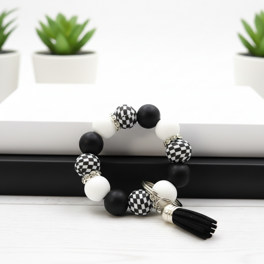 Black and white beaded bracelet on a white surface with green plants in the background