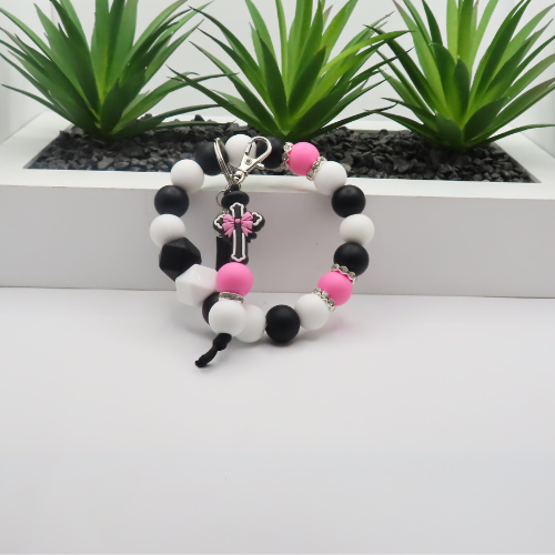 Beaded keychain with pink bow on a white surface with plants in the background