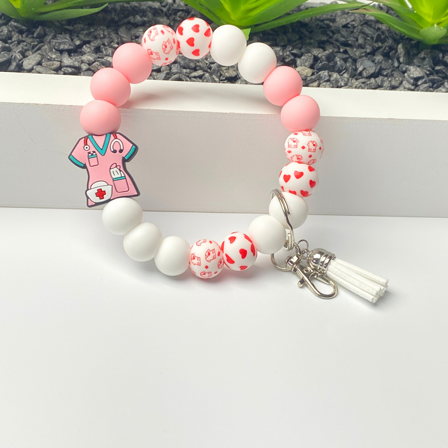 Beaded bracelet with a pink medical-themed charm on a white surface.