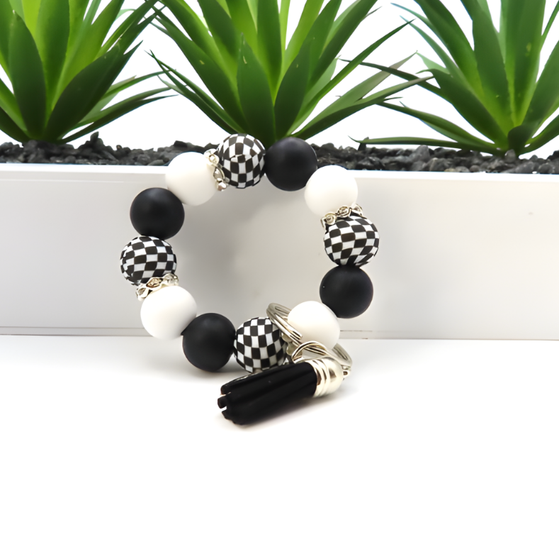 Black and white beaded bracelet on a white surface with green plants in the background