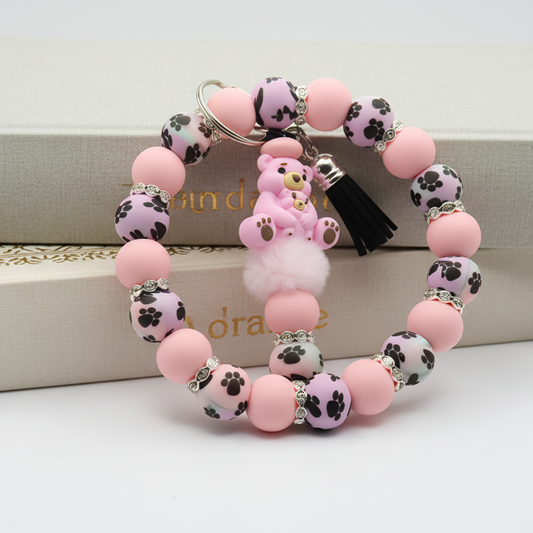 Pink beaded bracelet with paw print design on a white surface