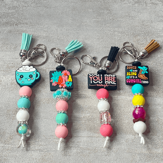 Colorful keychains with beads and decorative elements on a gray surface