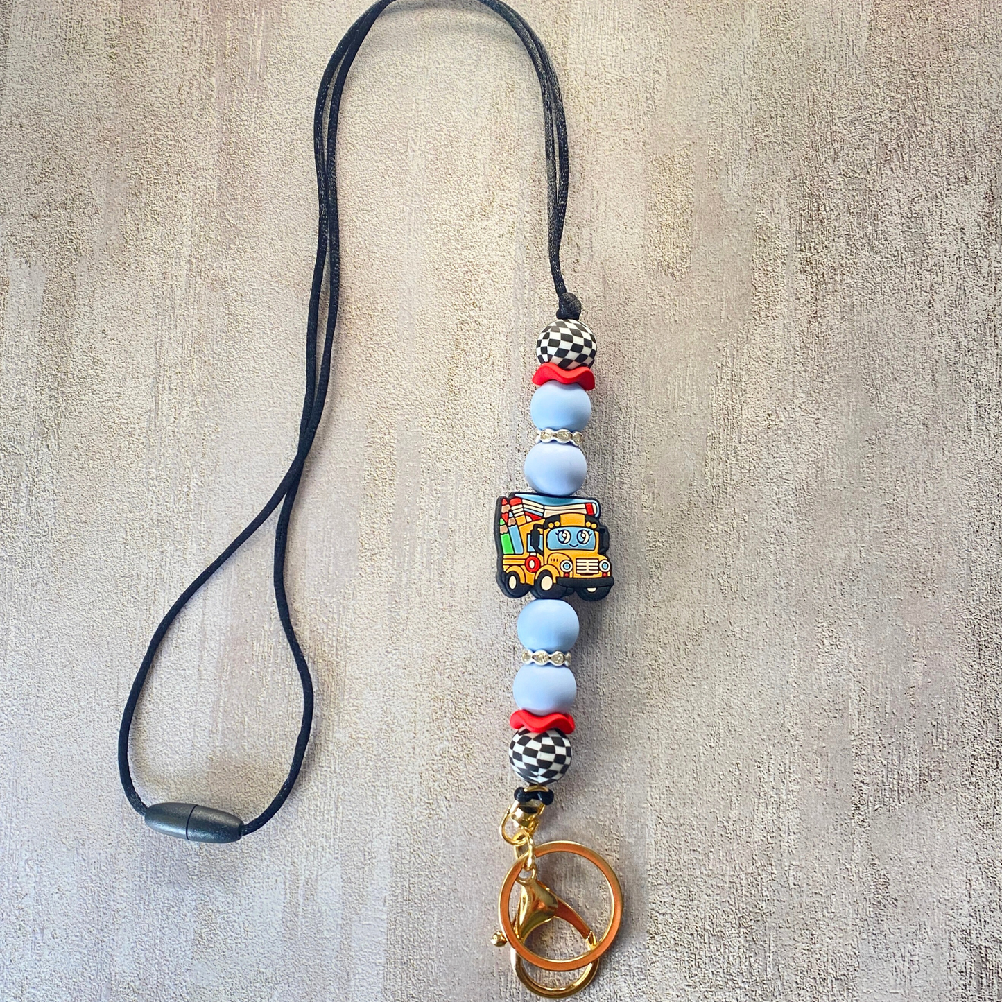 Phone lanyard with colorful beads and a keychain on a textured beige background