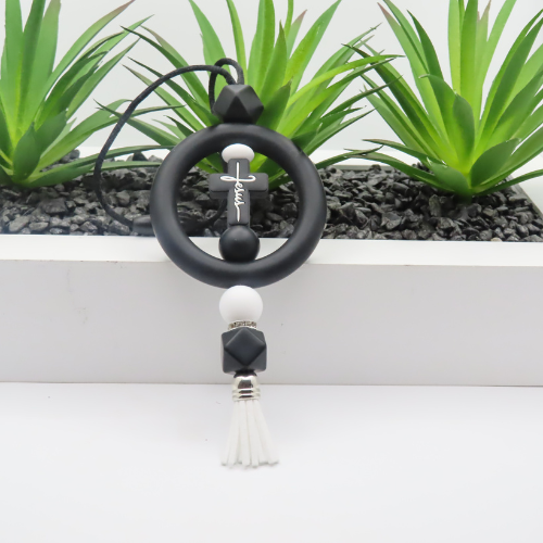 Black and white tassel keychain with plants in the background