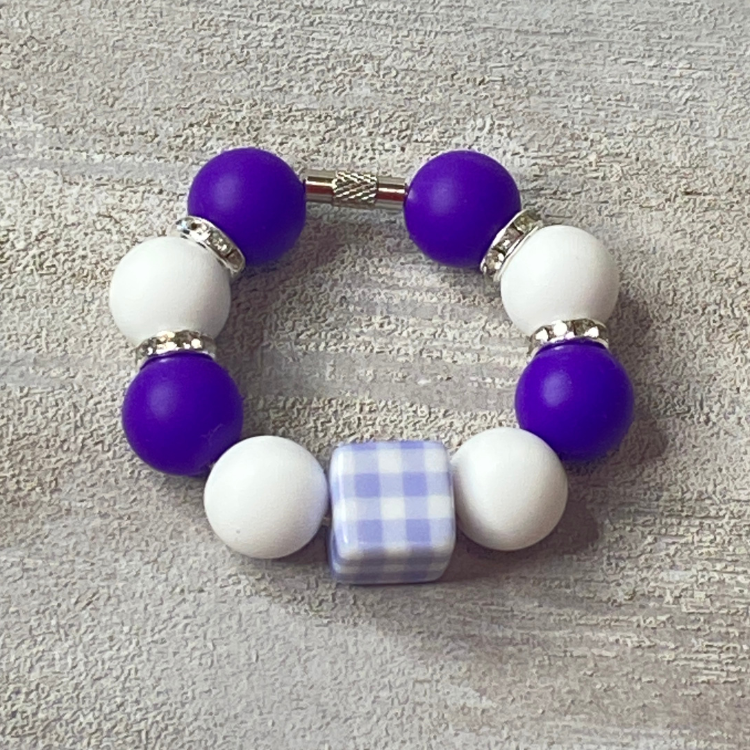 Beaded bracelet with purple and white beads on a textured surface