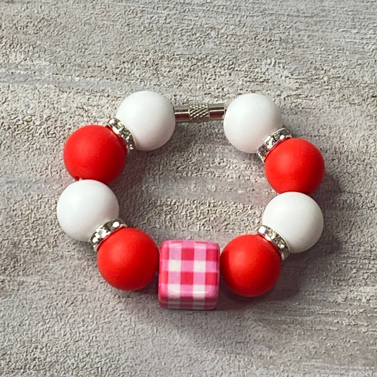 Bracelet with red and white beads on a gray textured surface