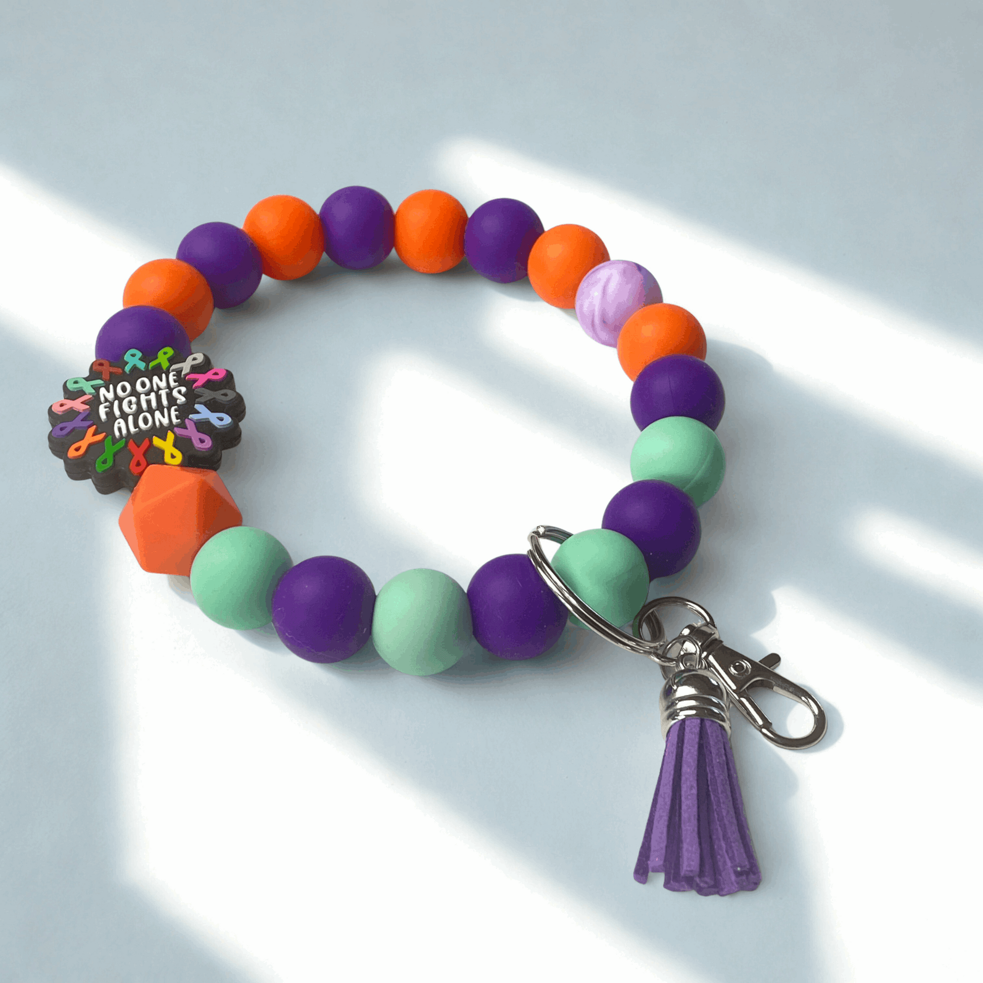Colorful beaded bracelet with a keychain and charm on a light background