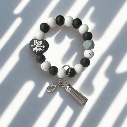 Black, white, and gray beaded bracelet with a keychain charm on a light background