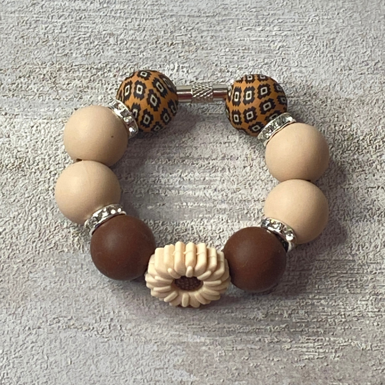 Bracelet with brown, beige, and patterned beads on a textured surface