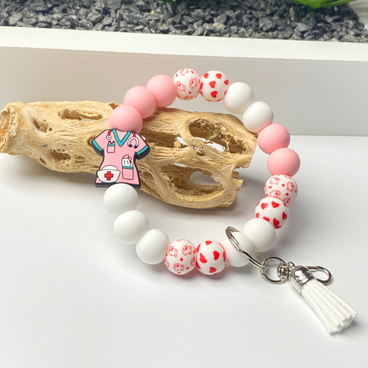 Beaded bracelet with pink and white beads and a keychain charm on a white surface.