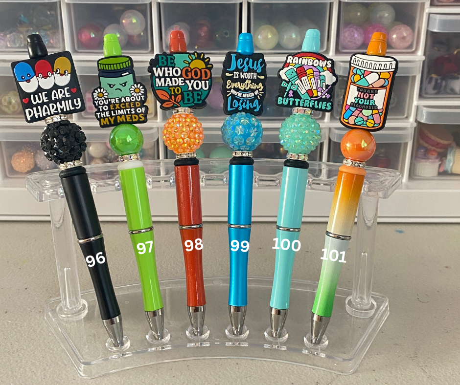 Colorful pens with various designs on a clear stand against a blurred background