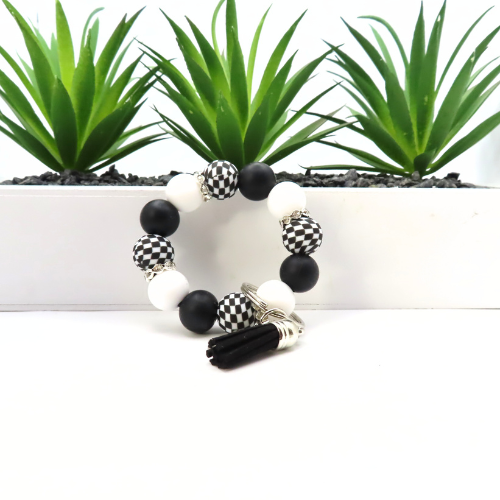 Black, white, and silver beaded bracelet with plants in the background