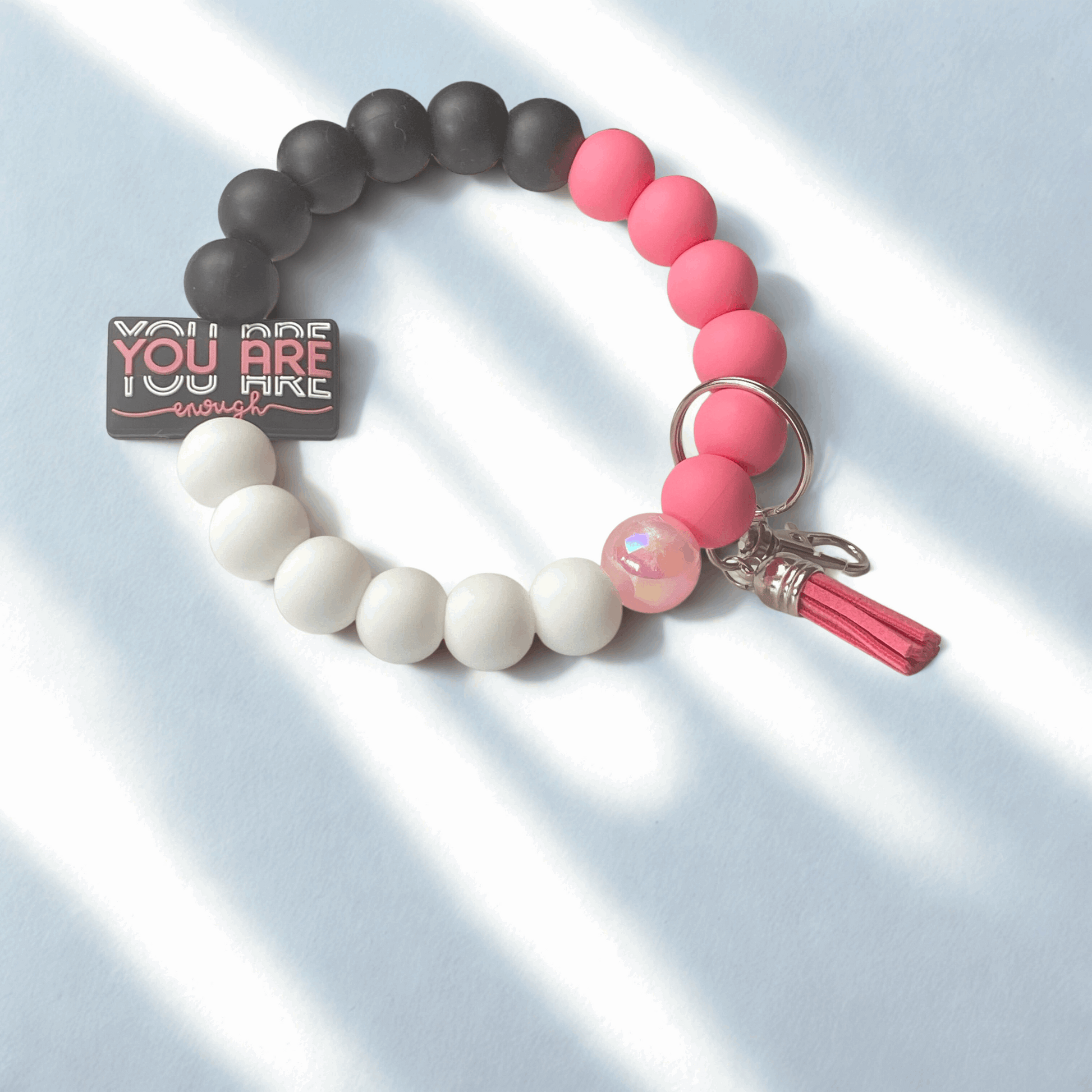 Beaded bracelet with pink, white, and gray beads on a light blue background