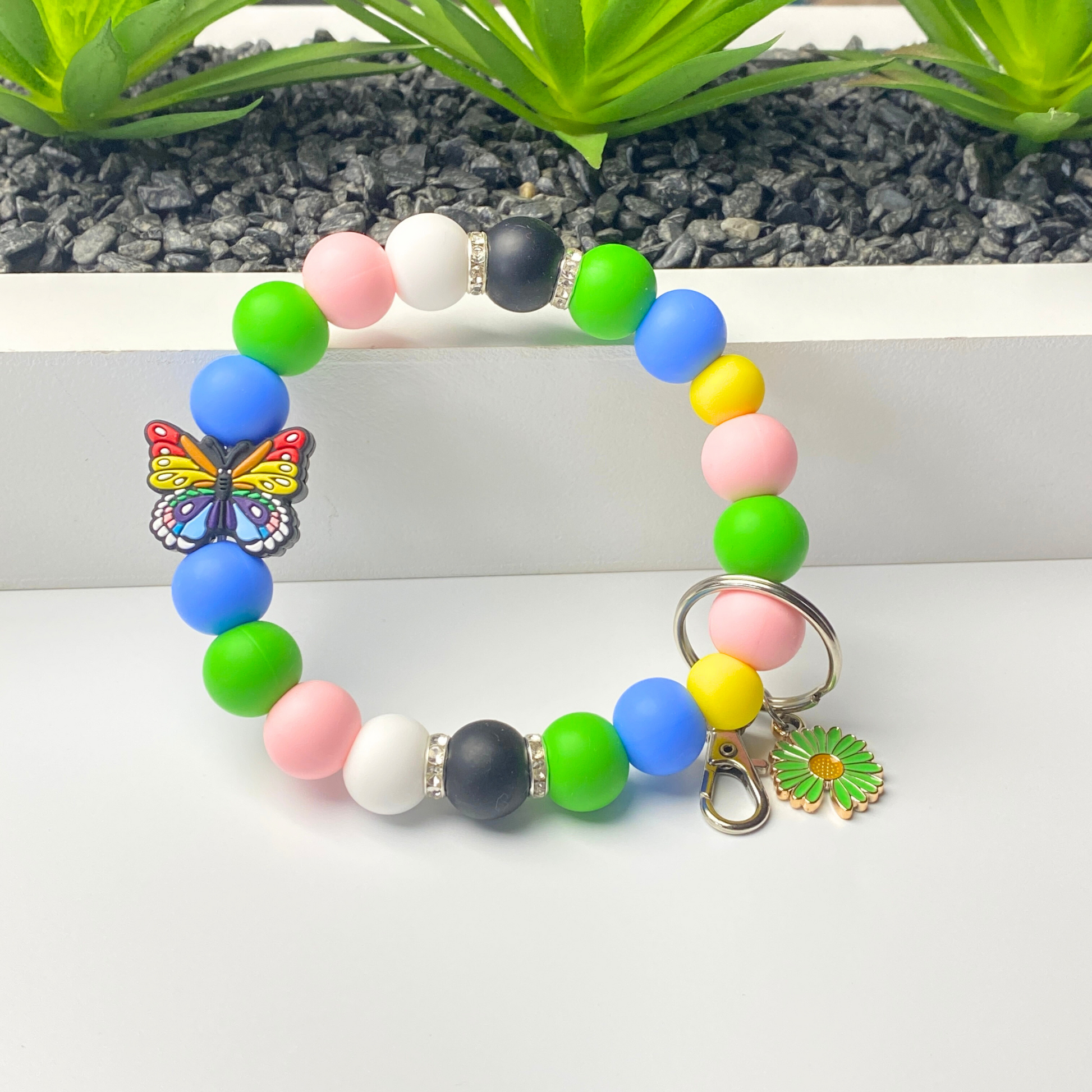 Colorful beaded bracelet with a butterfly charm on a white surface.