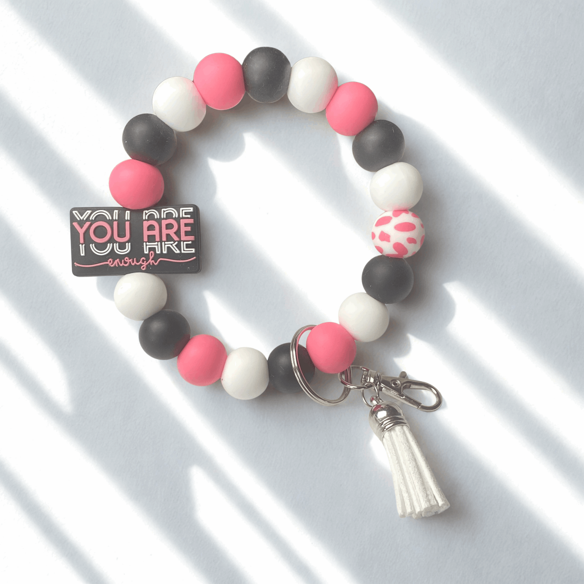 Beaded bracelet with pink, black, and white beads on a white background
