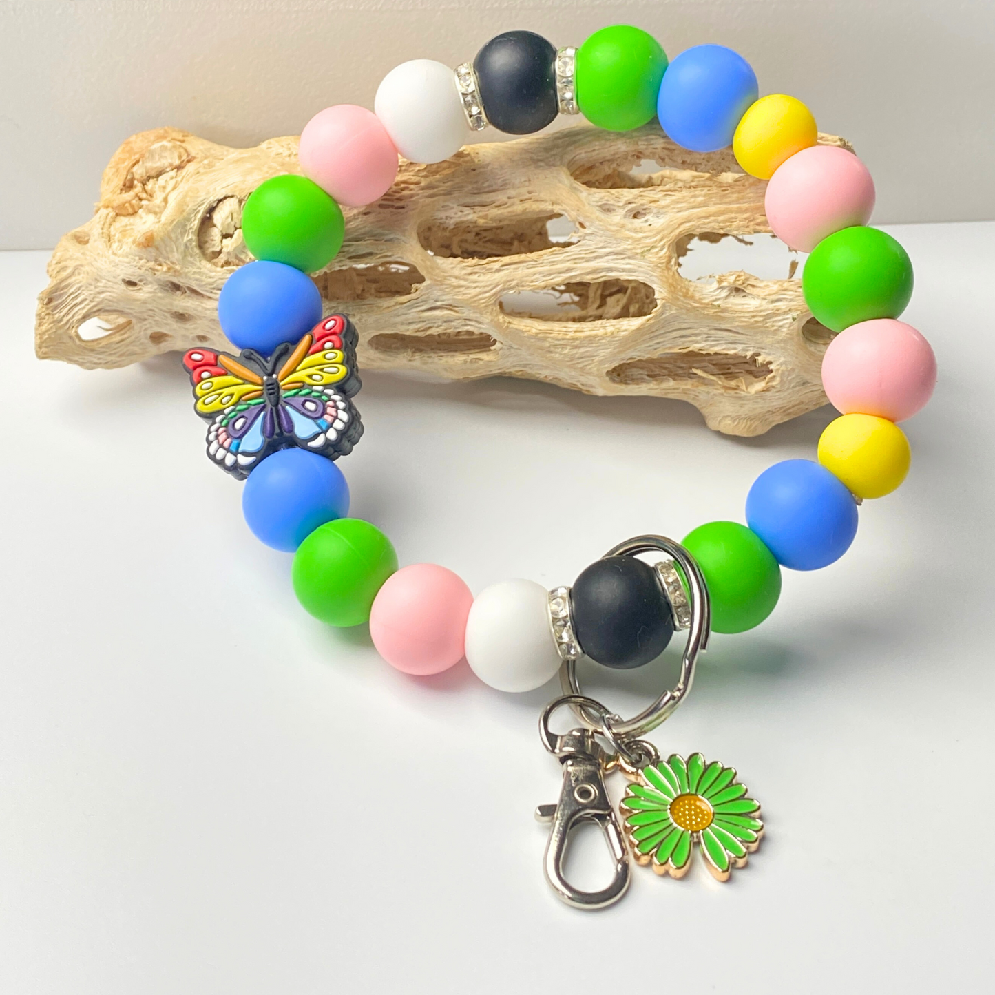 Colorful beaded bracelet with a butterfly and flower charm on a light background