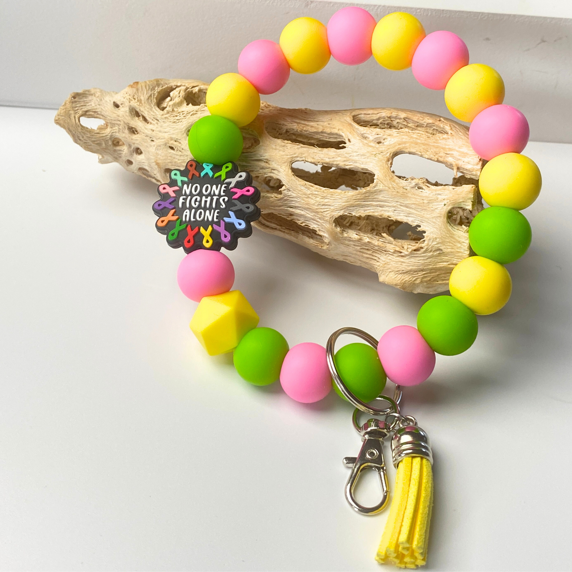 Colorful beaded keychain with a metal clasp and yellow tassel on a white background.