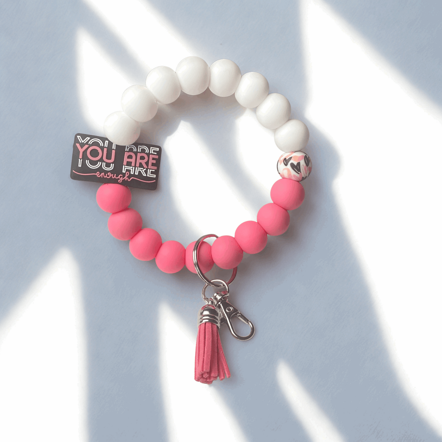Bracelet with pink beads and a tassel on a light blue background