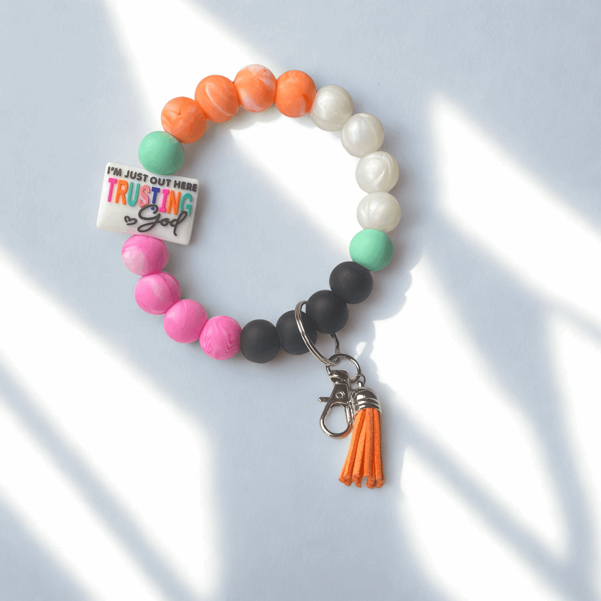 Colorful beaded bracelet with a tassel charm on a light blue background