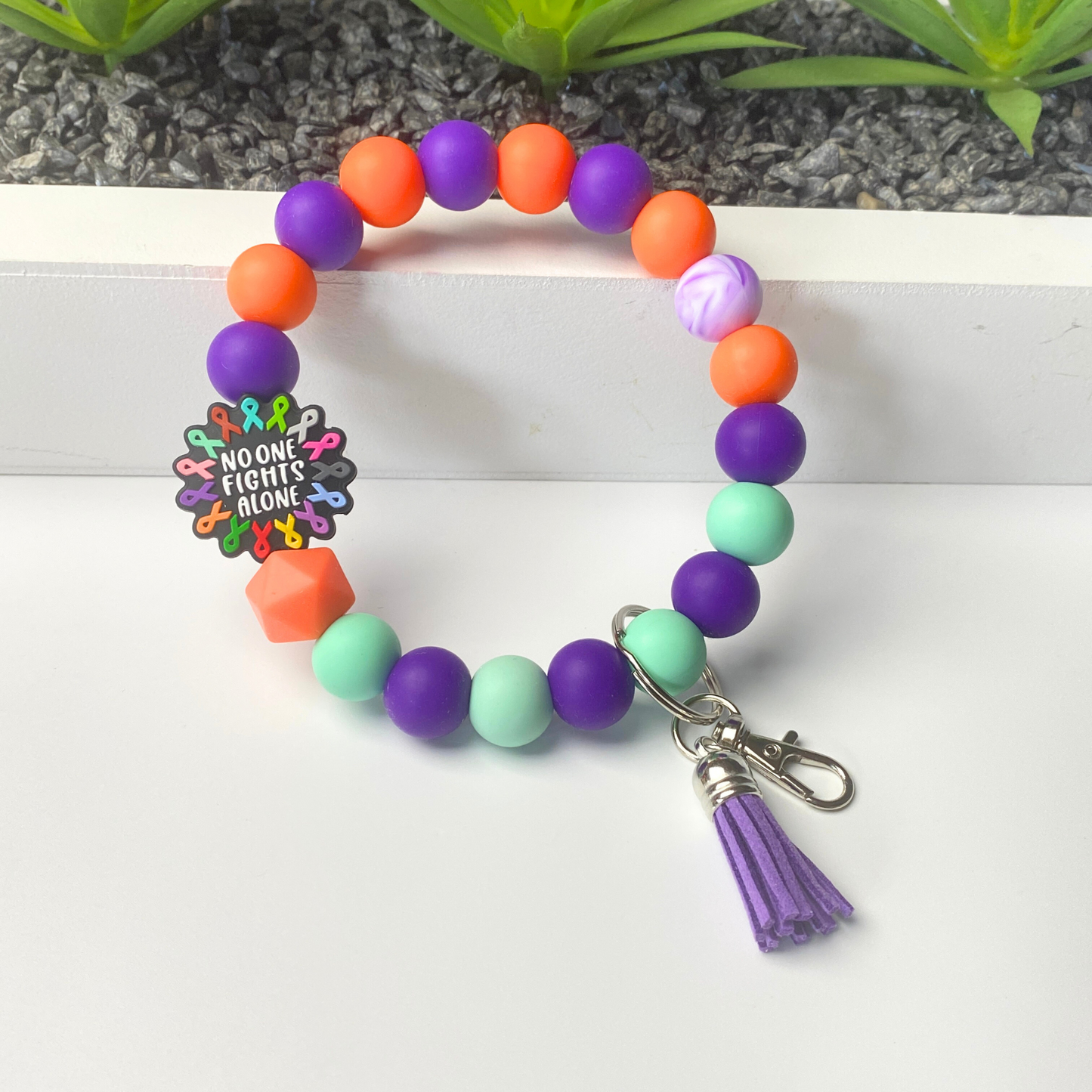 Colorful beaded bracelet with a keychain and tassel on a white background