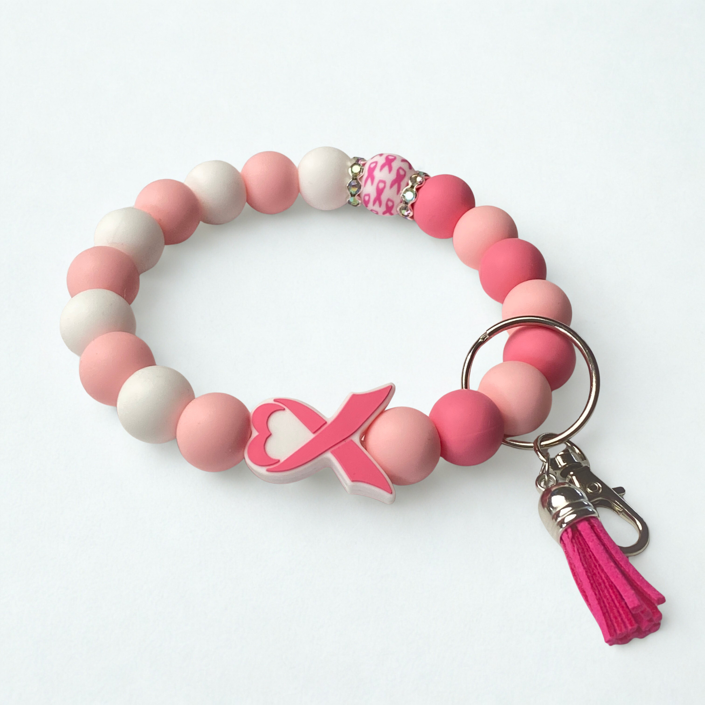 Pink and white beaded bracelet with a keychain and tassel on a white background