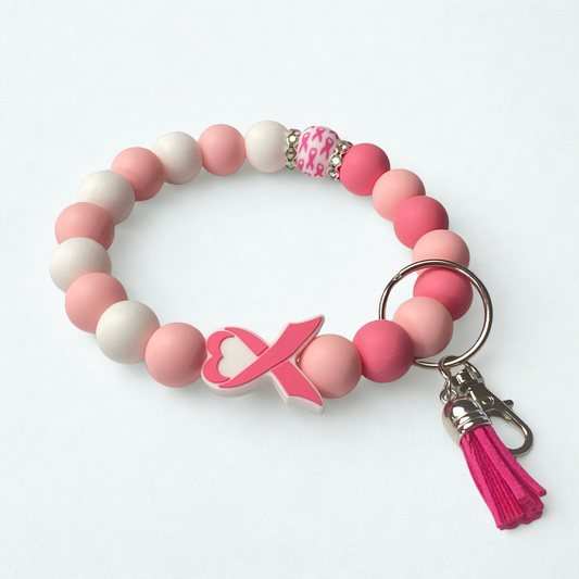 Pink and white beaded bracelet with a keychain and tassel on a white background