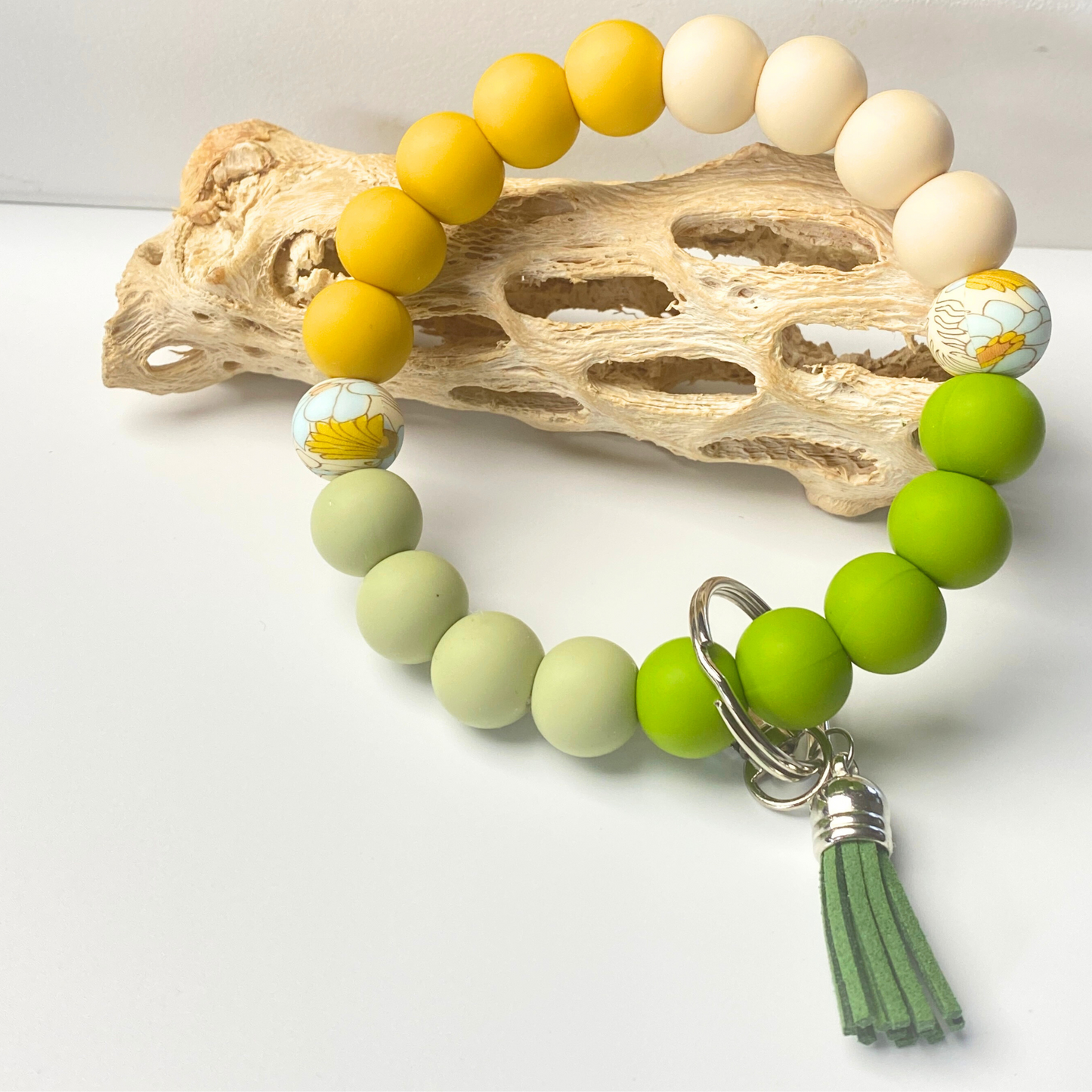 Green beaded bracelet with a tassel charm on a white background