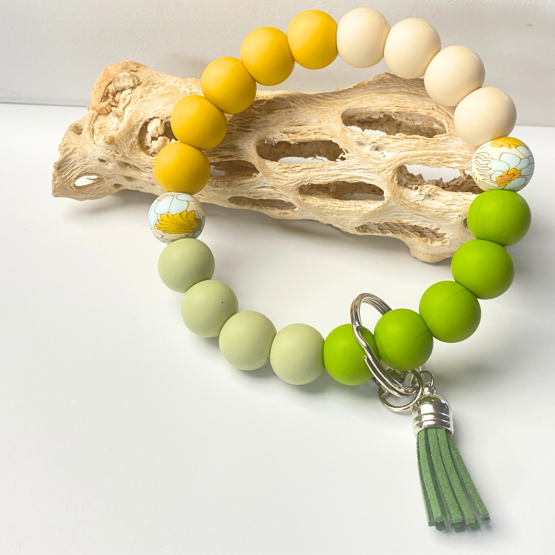 Green beaded bracelet with a tassel charm on a white background