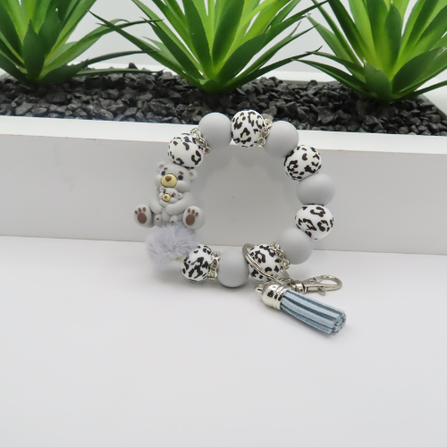 Bracelet with animal print beads and a keychain on a white surface with plants in the background