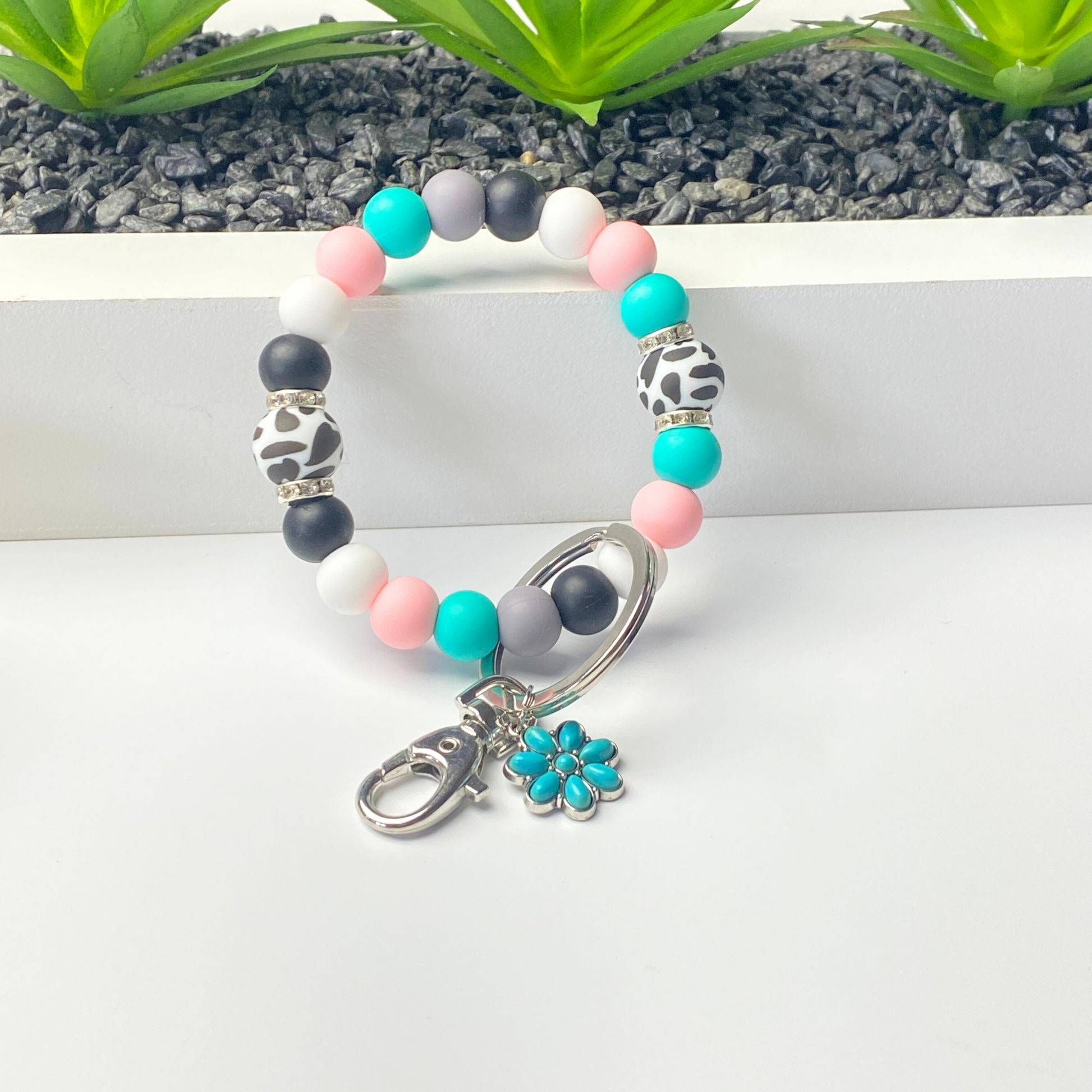Colorful beaded bracelet with a silver clasp and turquoise flower charm on a white surface.