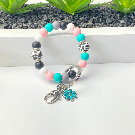 Colorful beaded bracelet with a silver clasp and turquoise flower charm on a white surface.
