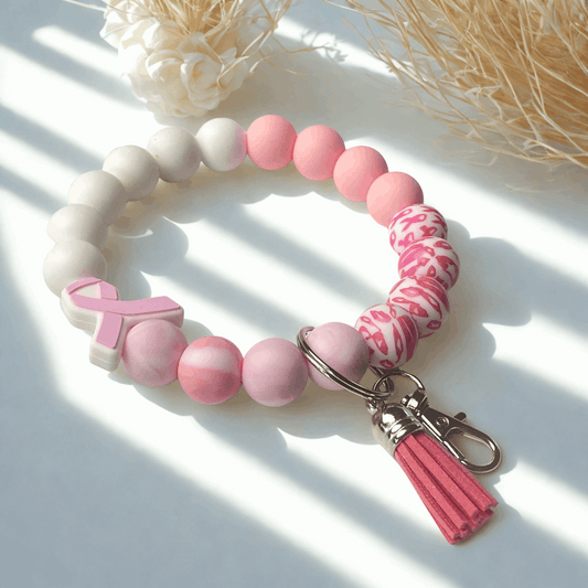 Pink and white beaded keychain with a breast cancer awareness ribbon on a light background