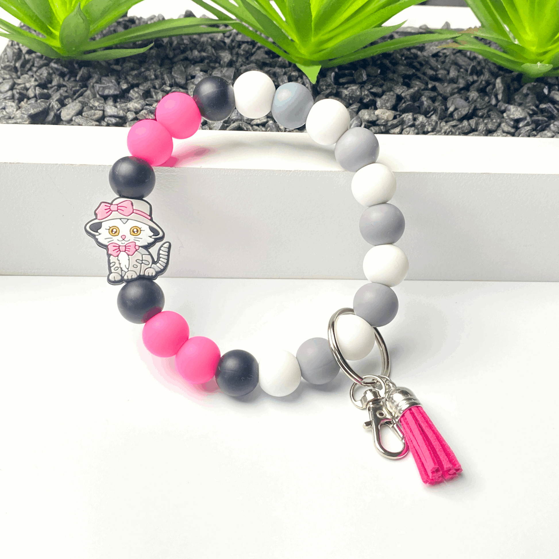 Colorful beaded bracelet with a character charm and tassel on a white background