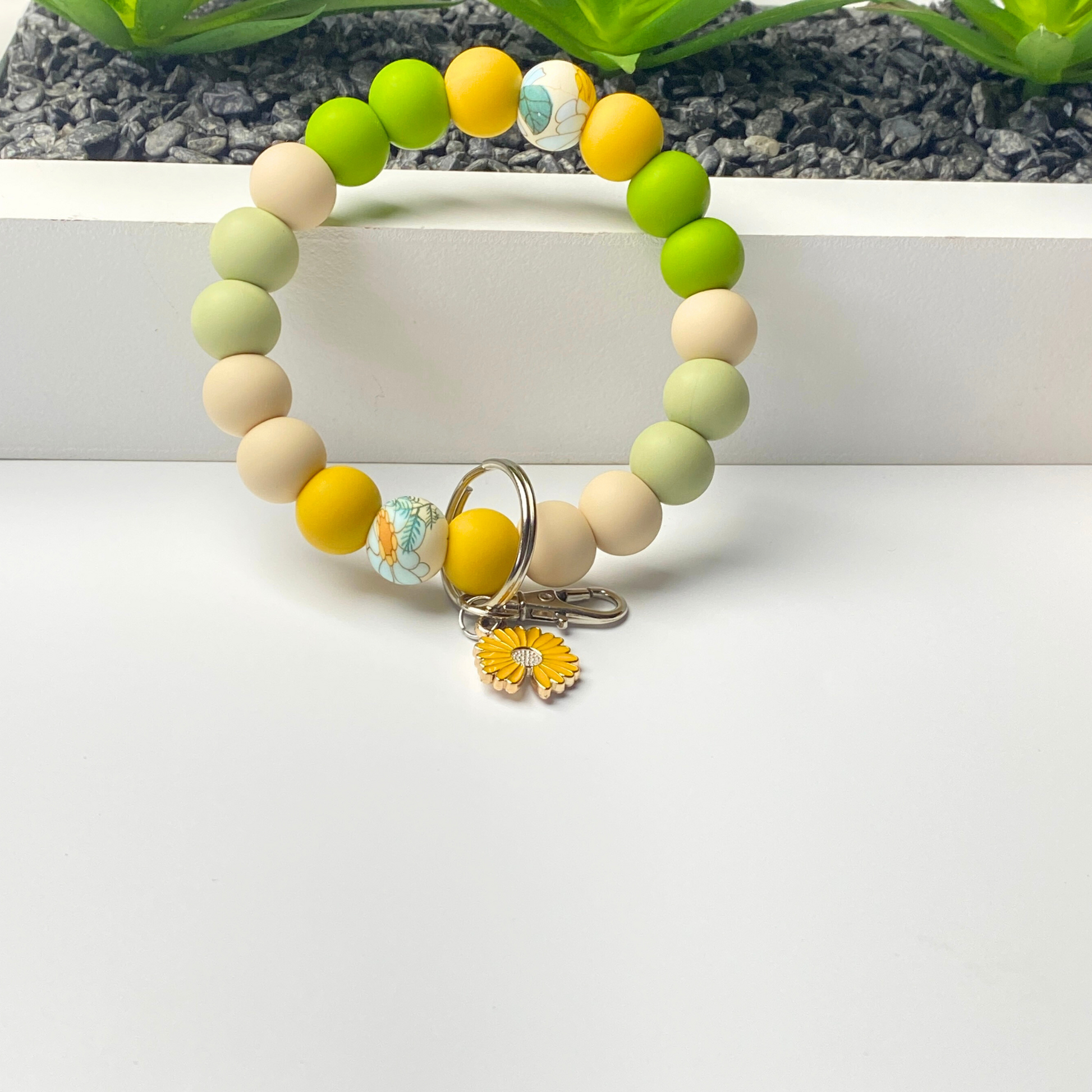 Beaded bracelet with colorful beads and a keychain charm on a white surface.