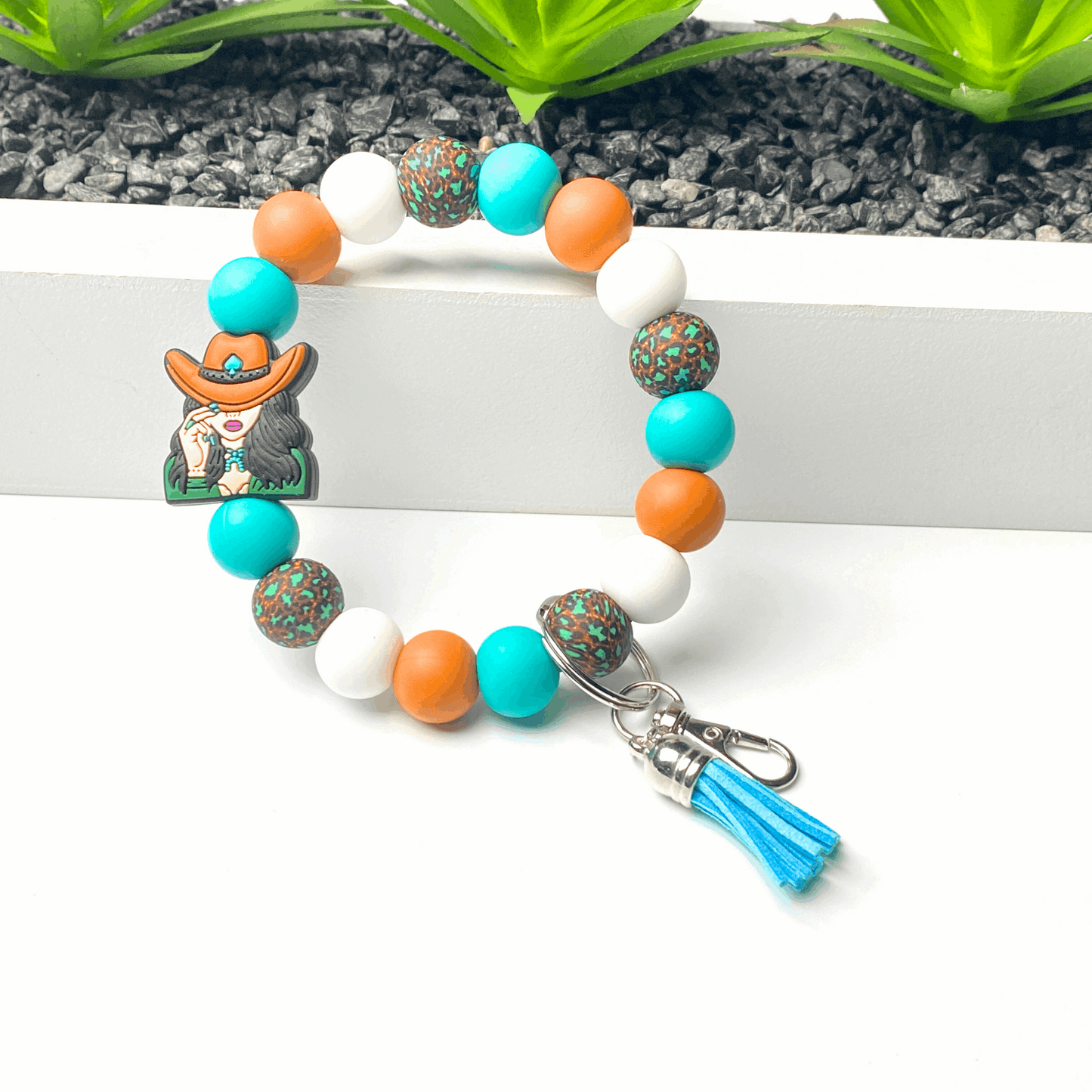 Colorful beaded bracelet with a keychain and tassel on a white surface.